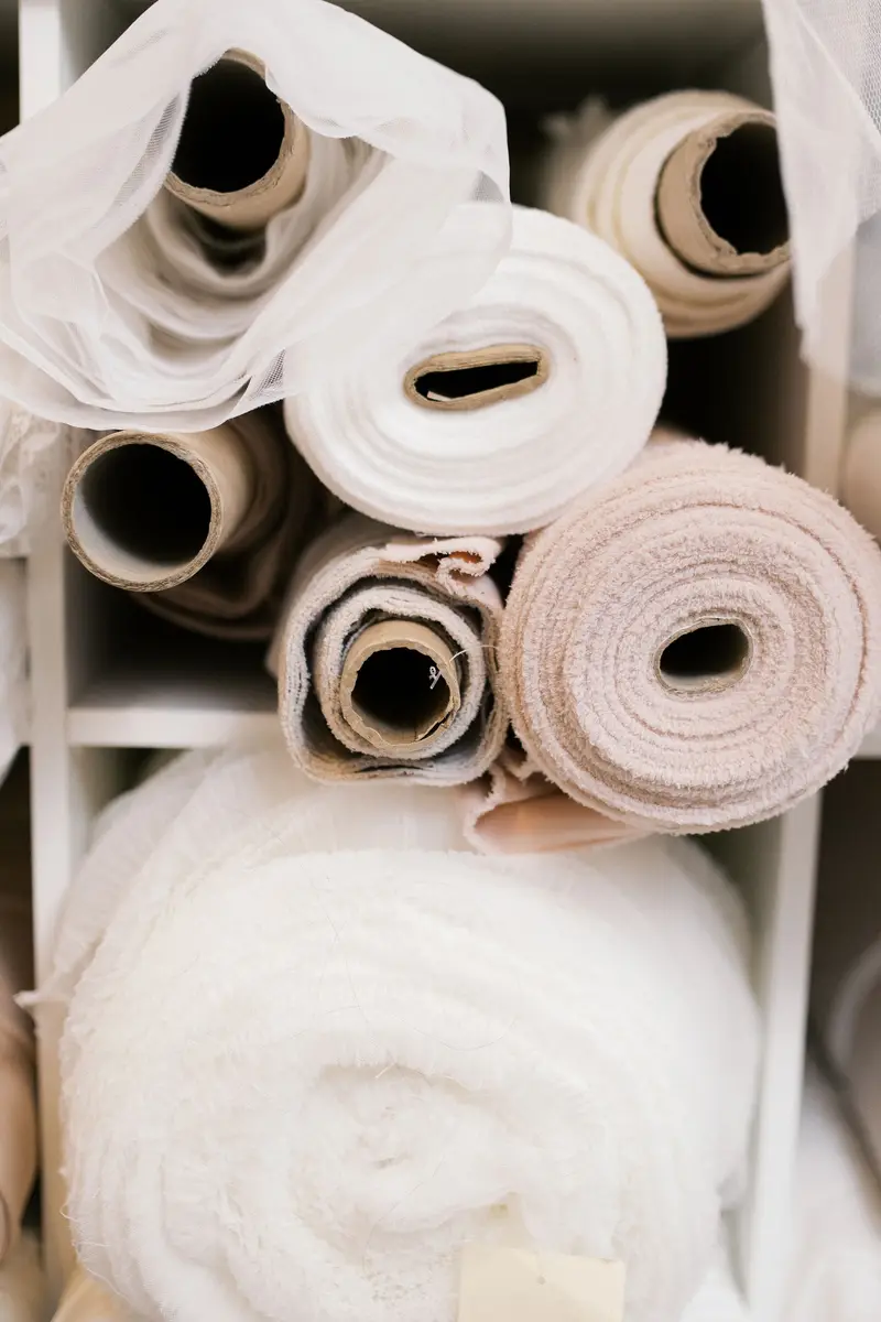Bridal fabric samples in ivory and champagne laid out on a table at Cande Bridal Boutique