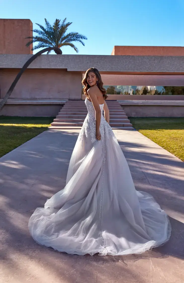 Back view of a Madison James gown, lace bodice with covered buttons down the spine and a tulle A-line overskirt with a long train