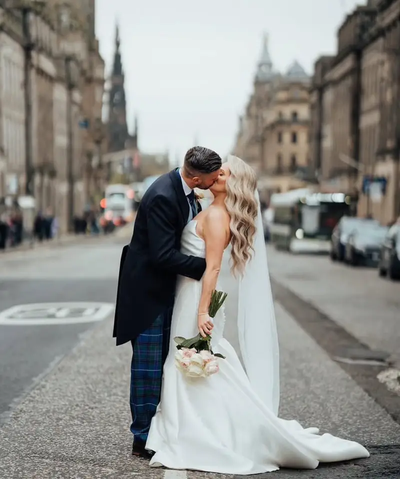 A bride from an independent bridal boutique in her wedding gown on a stone street in Edinburgh