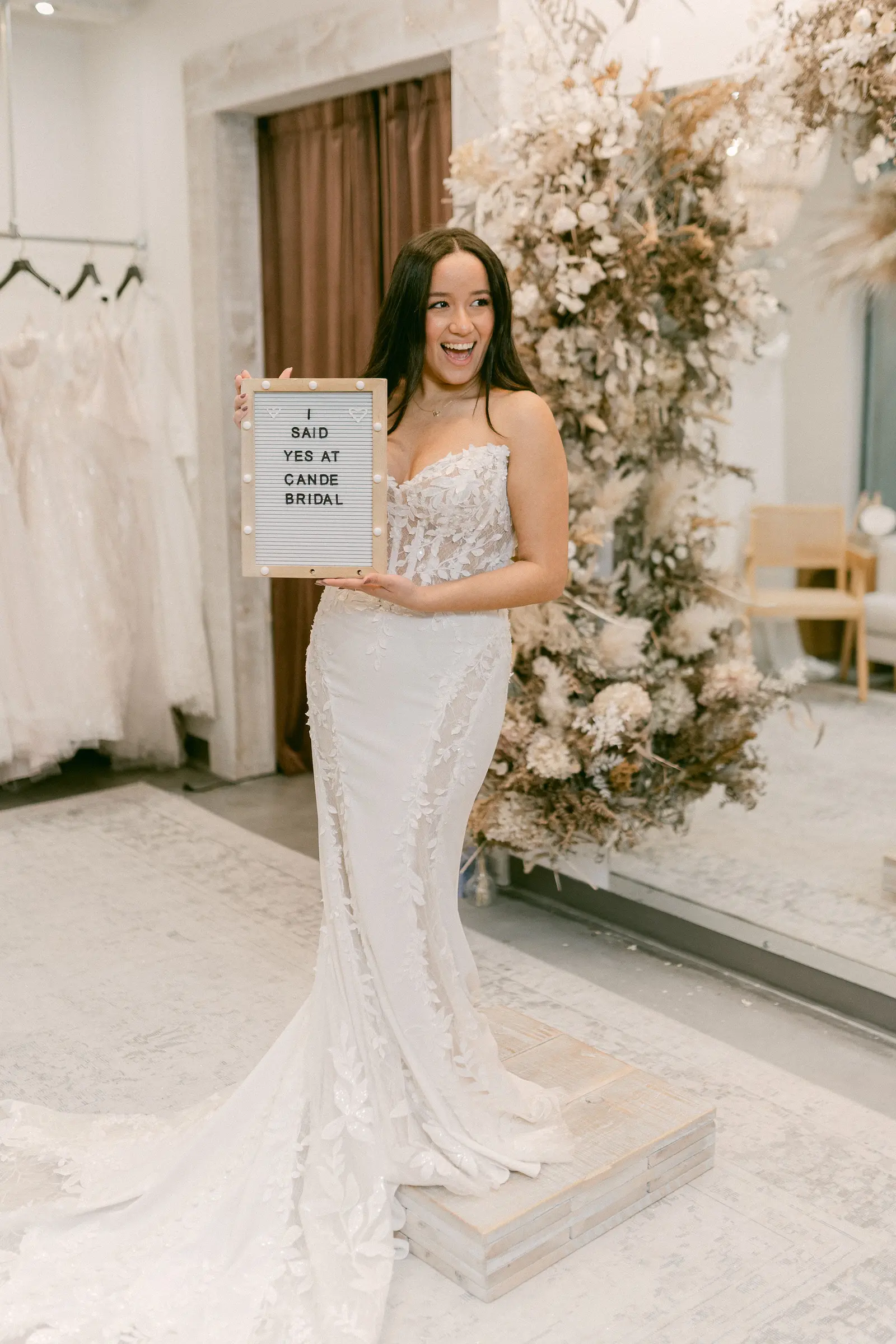A bride in a wedding gown in the moment she chooses it, seen close